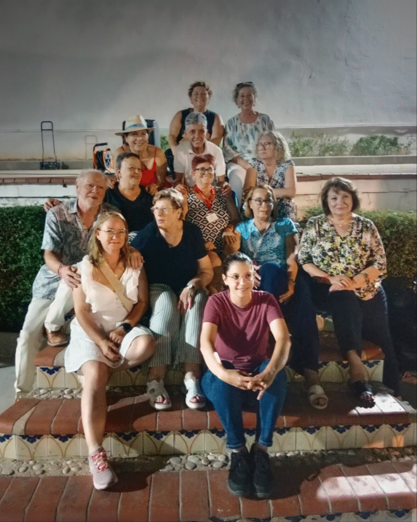 Grupo de voluntarios de Amunt contra el Càncer en la verbena solidaria en La Xara posando juntos durante la celebración.